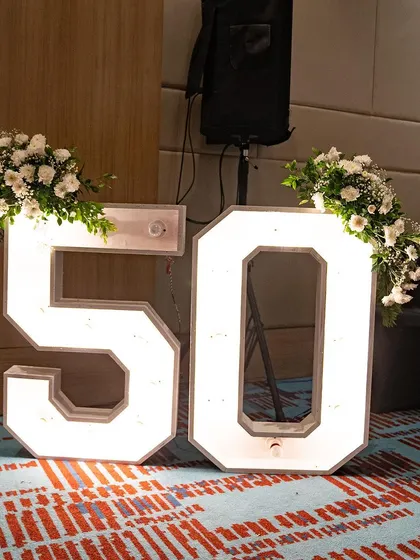 These light-up marquee numbers, decorated with fresh flowers, were a chic and modern decor element for the 50th birthday party. They provided a great photo opportunity and reinforced the milestone theme.