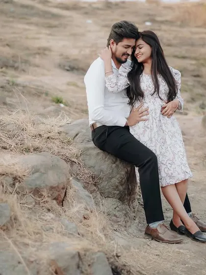 A close-up of their embrace on the rocks. The focus is on their connection and the beautiful, soft light of the evening.