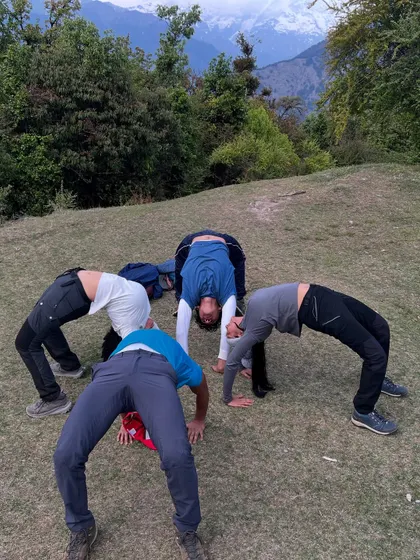 A playful moment with fellow trekkers as we all try Chakrasana, the wheel pose. Yoga on the trail is also about connection, laughter, and supporting each other's practice, no matter the level.