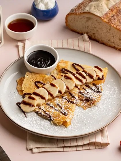 I also make classic French crepes. Here they are served simply with sliced bananas and a generous drizzle of chocolate sauce, perfect for breakfast or dessert.