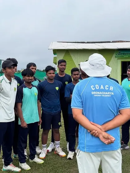 A coach imparts instructions to a group of young, attentive players. At our academy, every word from a coach carries the weight of experience and is a lesson in discipline and game strategy.