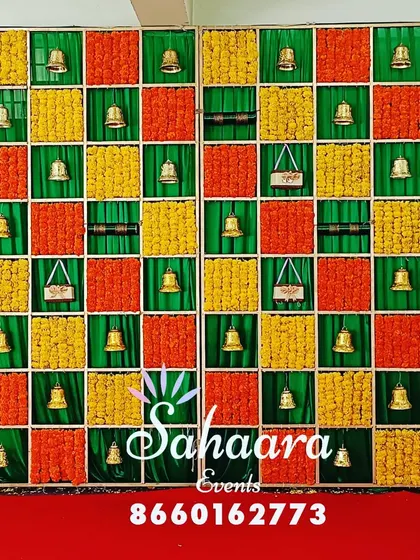 A vibrant and colorful backdrop perfect for a baby shower. The grid design is filled with orange and yellow marigolds and decorated with small brass bells for a festive look.