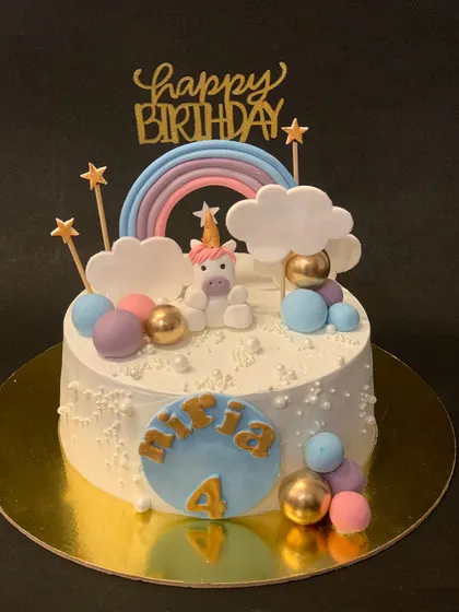 A whimsical unicorn cake with a pastel rainbow and clouds. The little fondant unicorn sitting on top makes it extra special for a 4th birthday.