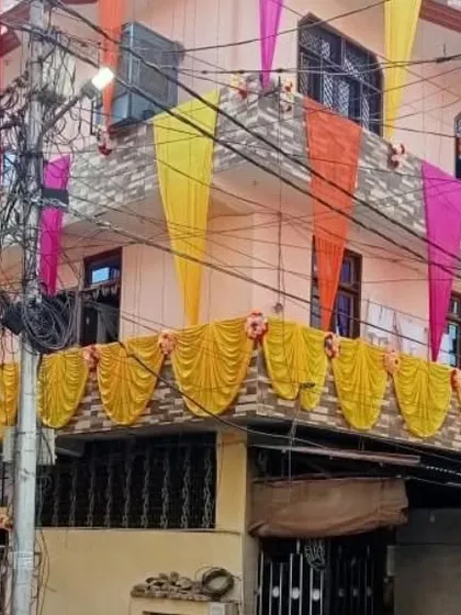 A house facade decorated with drapes in multiple colors, including pink, yellow, and orange.