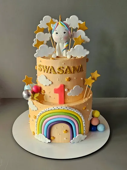 A peachy unicorn cake for Swasana's first birthday. This vanilla cake with salted caramel features a cute unicorn, a pastel rainbow, and fluffy clouds.