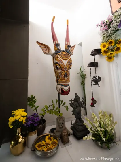 A corner of the home decorated for the welcome ceremony, featuring a traditional Pichwai cow head, a Ganesha idol, and various floral arrangements.