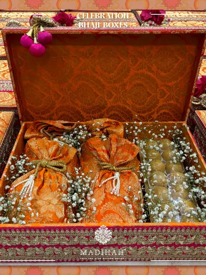A look inside the Celebration Bhaji Box, where brocade potlis and a selection of Indian sweets are nestled amongst baby's breath. It's a gift that feels abundant and heartfelt.