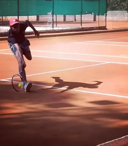 A player executes a low volley with impressive agility during the Tennis360 Open Tournament.