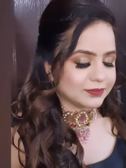 A soft glam party look with sparkling gold eyeshadow and a classic red lip, created by a student.