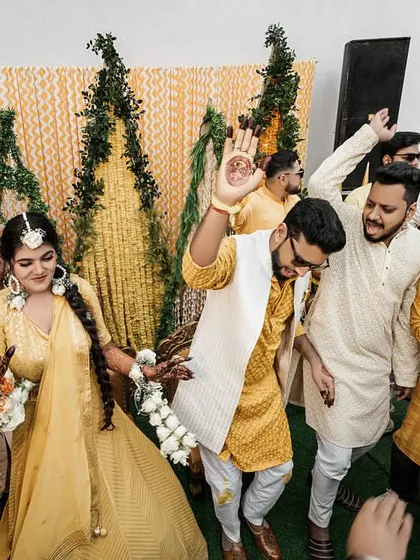 The bride and groom lead the dance party at their Haldi, surrounded by their friends and family in a sea of yellow.