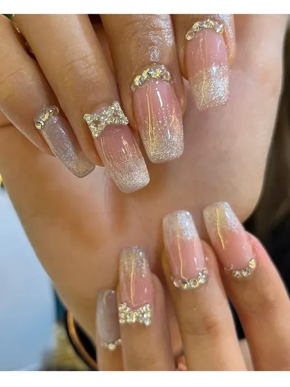 Go all out with this glamorous set. It features a glitter ombre effect on square-shaped nails, adorned with rhinestone-encrusted 3D bows and additional crystals at the cuticle for maximum sparkle.
