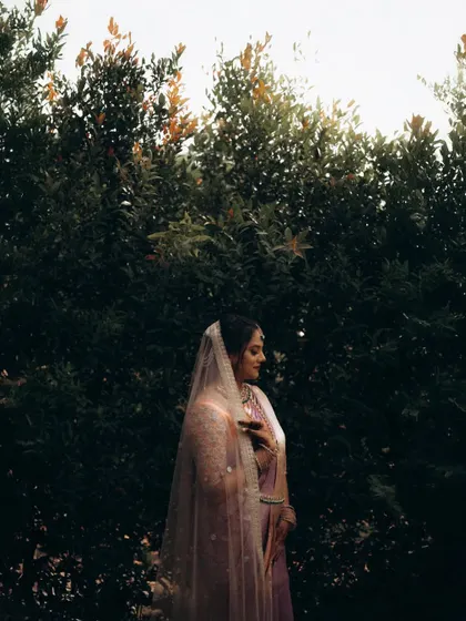 A moody and atmospheric shot of the bride with her veil. The dark, natural background makes her stand out, creating a very cinematic and mysterious portrait.