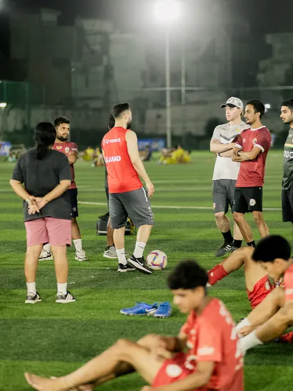 Coaches and players discuss strategy during a break in training. These camps are not just about physical drills but also about fostering football intelligence and teamwork.