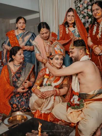 The groom places the sacred necklace, a pivotal moment in the ceremony, surrounded by the watchful eyes of their family.