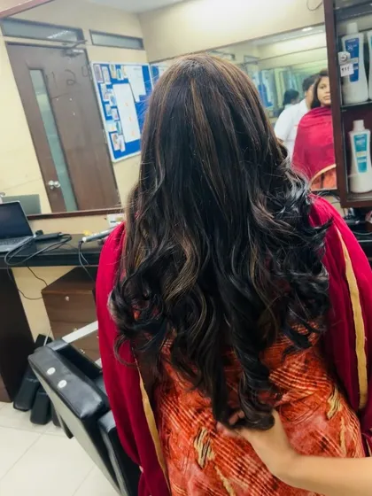 This side view showcases the seamless blend of the base color and the highlights, along with the soft, flowing curls created during styling.