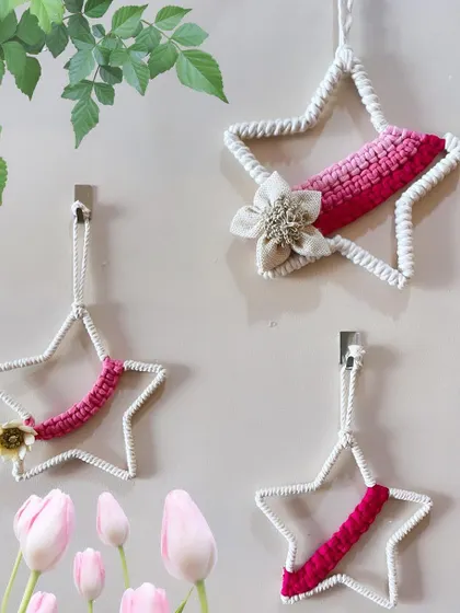A set of three star-shaped wall hangings. The simple white stars are accented with shades of pink and a small floral detail, making them a sweet addition to a girl's room.