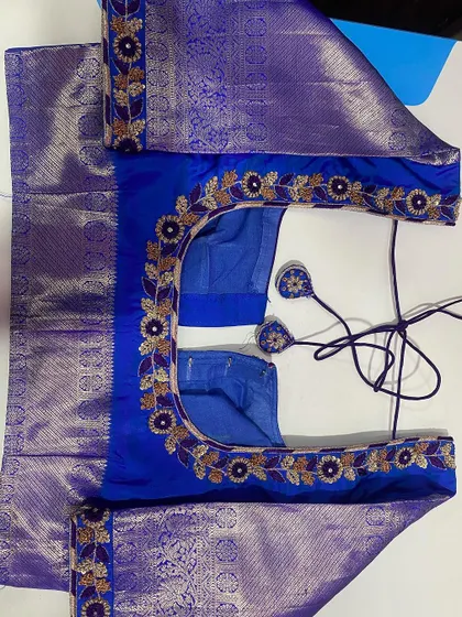 This royal blue blouse is made from silk with a silver Zari border. I added floral embroidery along the neckline that complements the saree border on the sleeves.