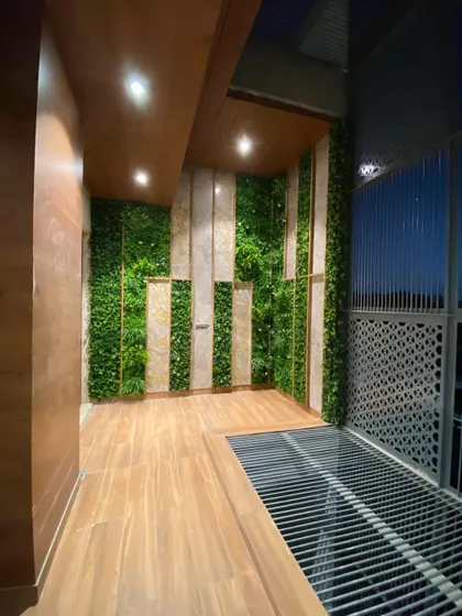 A back balcony wall in Faridabad is transformed with a vertical garden, alternating with panels of stone-look tiles and wood, creating a feature wall.