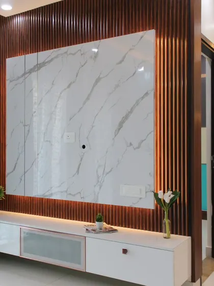A close-up of a floating entertainment unit that combines a white marble-finish backdrop with vertical wooden fluting and backlighting. This piece serves as a sophisticated focal point for the living room while offering practical, concealed storage.