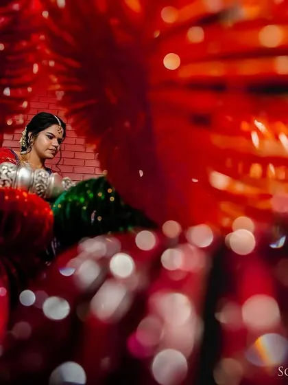 A creative shot of a bride through a frame of red bangles, creating a unique and colorful portrait.