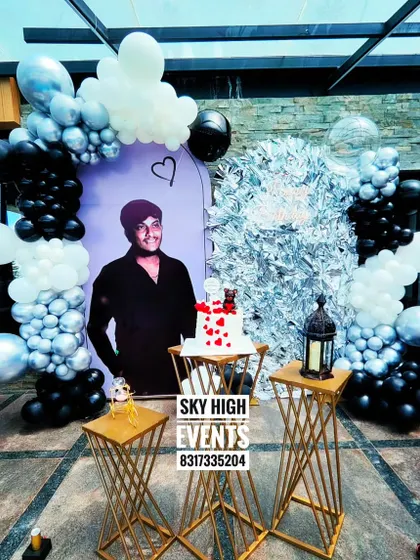 A surprise birthday setup for a special someone. The black and silver theme with a personalized photo backdrop creates a sleek and heartfelt celebration.