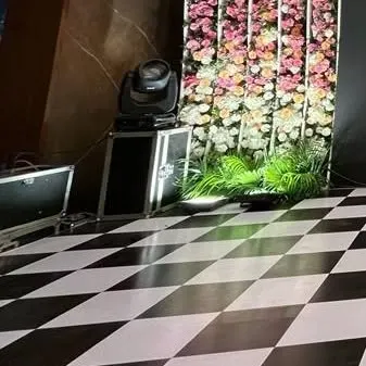 A classic black and white checkered dance floor paired with a floral backdrop and professional stage lighting. We provide a variety of flooring and staging options to suit any theme.