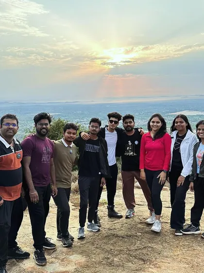 A team poses for a photo as the sun rises over the horizon during our Skandgiri sunrise trek. It is an early start, but the view is always worth it.