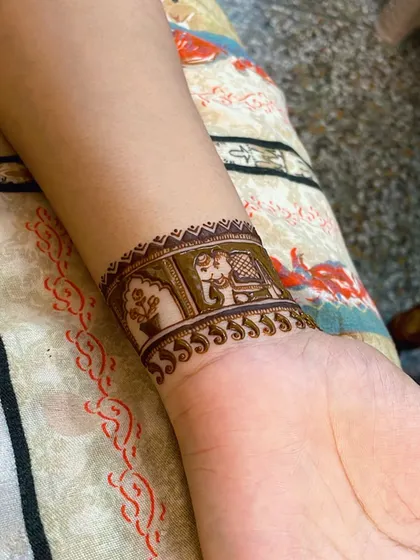 A simple yet elegant wrist cuff design. This pattern includes a small elephant and a floral motif, perfect for a minimalist festive look.