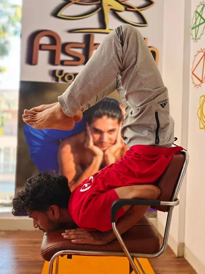 An incredible display of flexibility and strength, using a chair to support a deep scorpion pose variation.