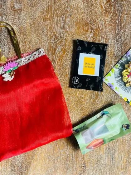 A deconstructed view of a red Rakhi gift bag, showing the rakhi and other small tokens inside.