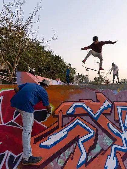 Painting a piece on a ramp while a skater flies by in the background. This captures the dynamic energy of painting in a live, active environment like a skatepark.