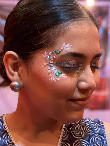 A close-up of an intricate eye design using glitter and multi-colored studs for a 3D effect.