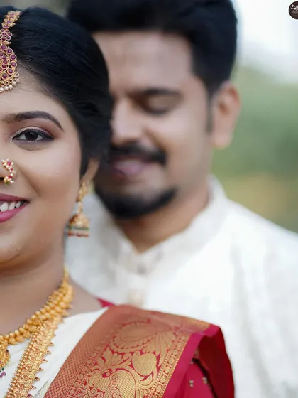 An artistic close-up of the bride's smiling face, with the groom positioned softly out of focus in the background. This composition creates a beautiful and modern wedding portrait.