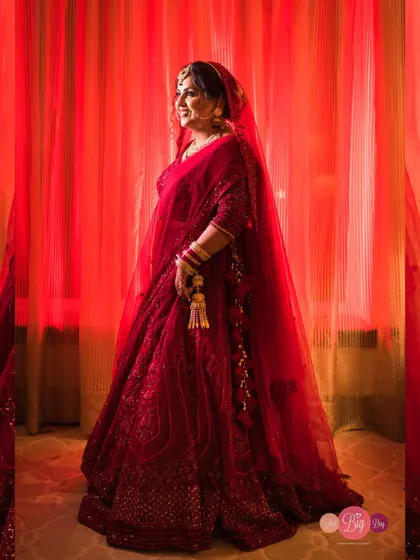 A portrait of the bride, Shivya, bathed in dramatic red light, highlighting the rich colour of her lehenga.