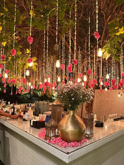 A beautifully decorated bar, with hanging lights and flowers, ready for service.