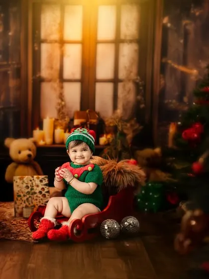 This little elf is ready for Christmas, sitting in a sleigh in a cozy, warmly lit room filled with presents and holiday cheer.