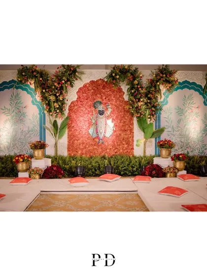 The stage for the Sagai and Mandap Muhurat, featuring a floral backdrop of Lord Shrinathji. The design combines traditional motifs with lush greenery for a fresh and sacred ambiance.