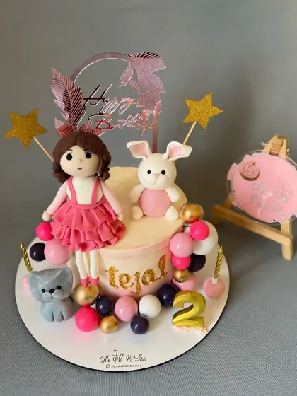 A sweet cake for a second birthday, featuring handmade fondant figures of a little girl, her bunny, and her cat.