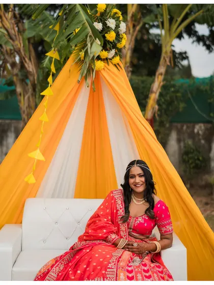 The bride sits happily in her bright pink lehenga during the Mehendi ceremony, ready for the celebrations.