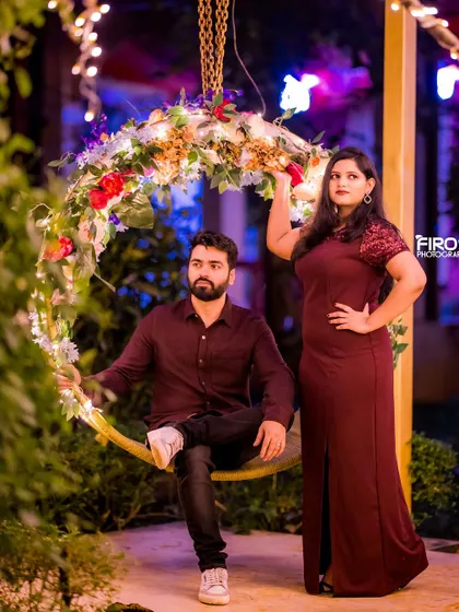 A stylish, editorial-style portrait on the floral swing at night. The couple's confident poses and the beautiful lighting create a high-fashion look.