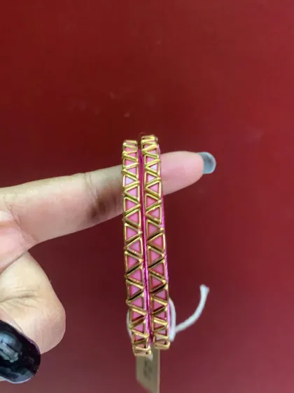 These slim pink bangles feature a modern, geometric gold-tone design. They are perfect for stacking with other bangles or wearing on their own.