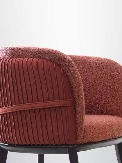 This armchair features a unique pleated back and a rich, textured fabric. It's a piece that adds a touch of luxury and personality to any room.