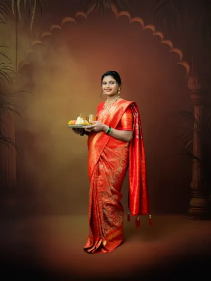 This full-length portrait showcases the elegance of a mom-to-be in a vibrant red saree. Holding a traditional thali, she embodies grace and cultural pride in our custom studio setting.
