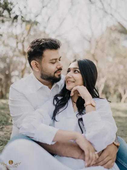 A sweet and candid moment of a couple sitting together in a park. The way they are looking at each other shows a deep and comfortable affection.
