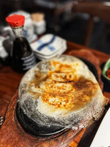 A sizzling platter of our Hanetsuki Gyoza, served straight from the pan. The crispy "wings" are a sign of a perfectly cooked gyoza.