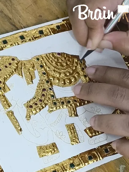 A student carefully applies gold foil to an elephant motif in a miniature Tanjore piece, a great project for beginners.