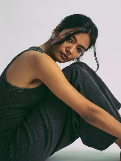 A relaxed, grounded pose. The simplicity of the outfit and the background keeps the focus entirely on the model's mood.