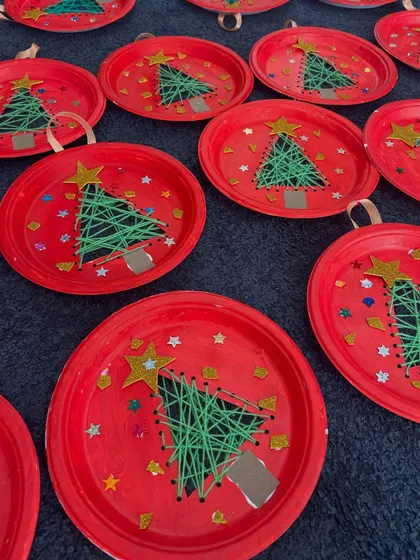 We used paper plates and yarn to create these unique Christmas tree string art ornaments. It's a great activity for developing fine motor skills.