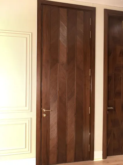 Another perspective of the chevron-patterned American walnut door, showing how it complements a classic paneled wall.