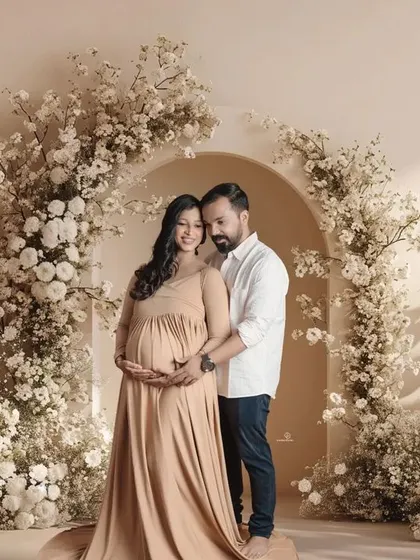 A stunning portrait of an expecting couple surrounded by a beautiful arch of white flowers. This setup creates a romantic and timeless feel for a studio maternity session.